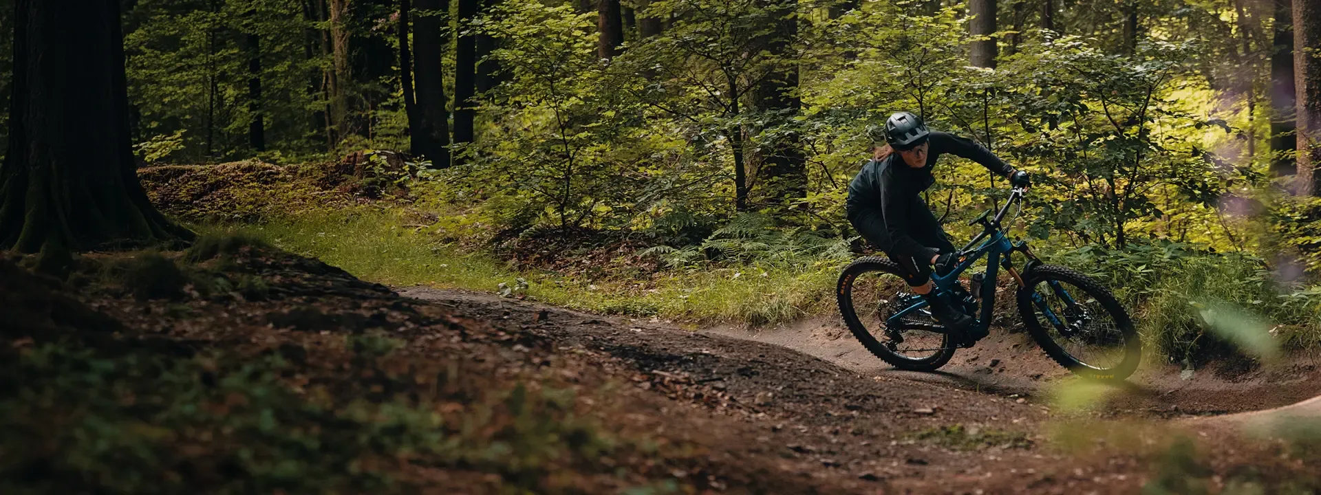Mountain biker riding through a corner on a wooded trail