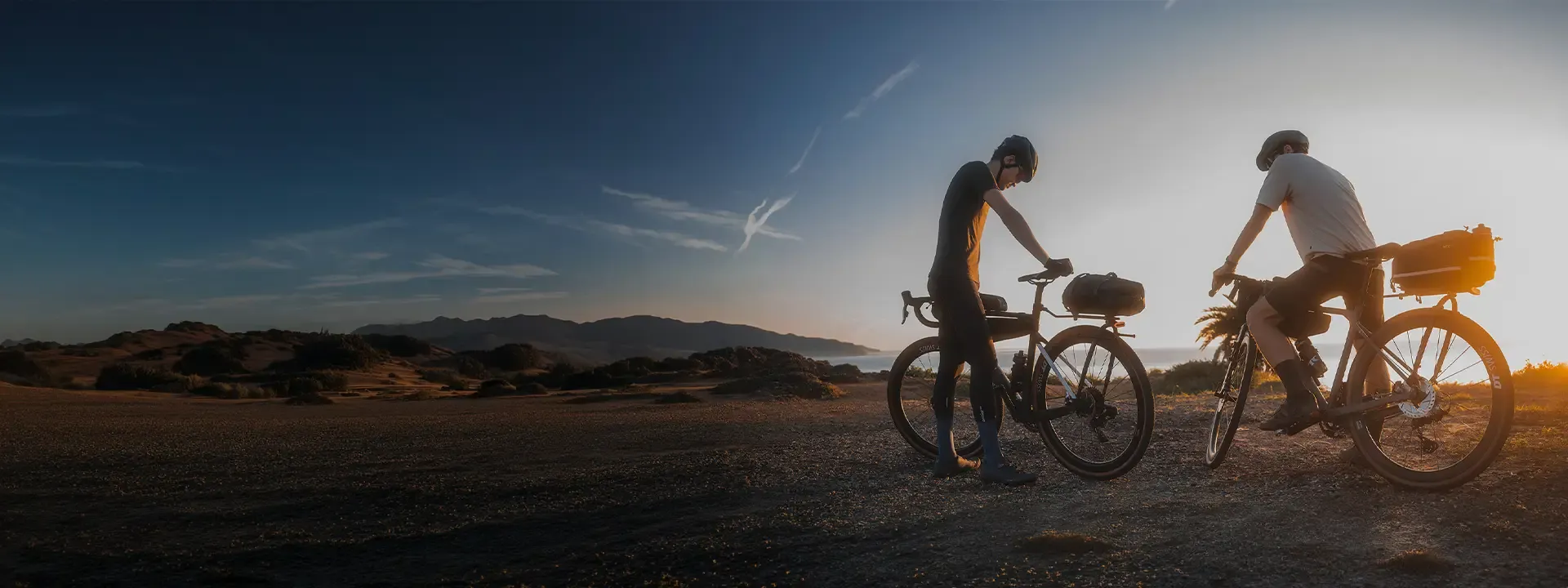 Two cyclists with luggage-equipped bikes enjoying an evening ride