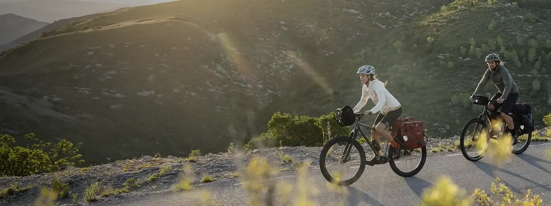Two touring cyclists carrying panniers on a mountain road