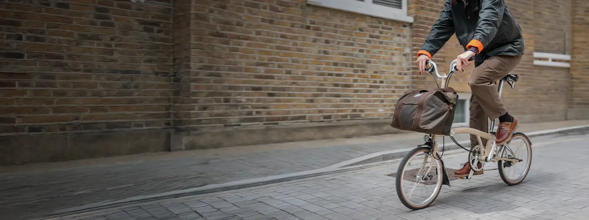 Cyclist riding a Brompton folding bike with a large front bag