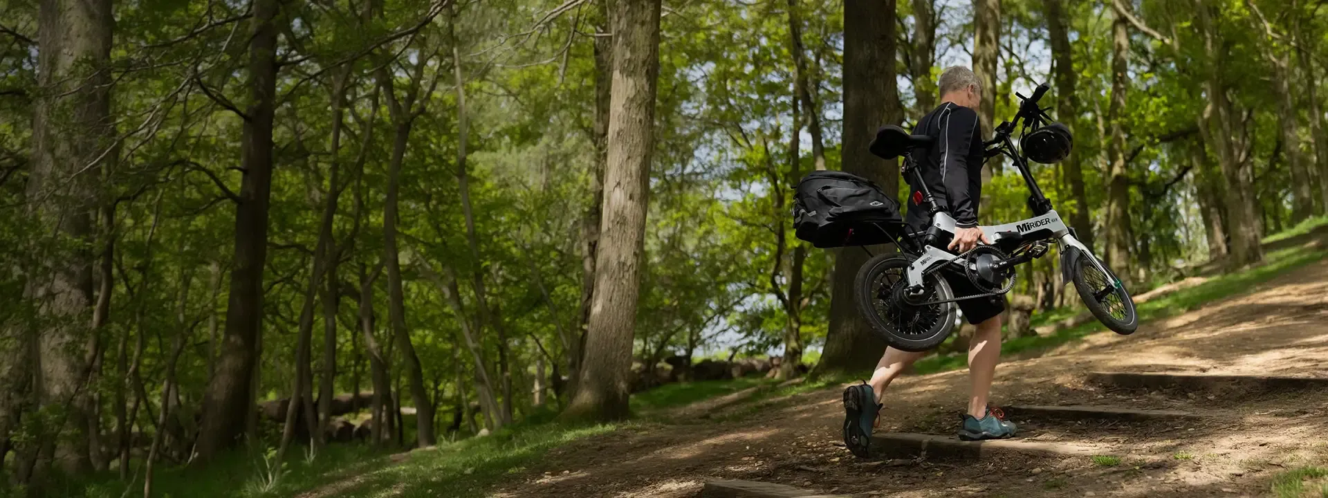 Rider carrying a folded MiRider electric bike with rear luggage