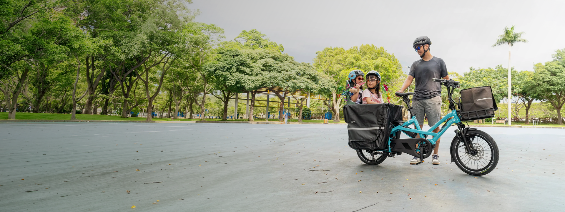 Family with a Tern cargo bike fitted with rear panniers and a front bag