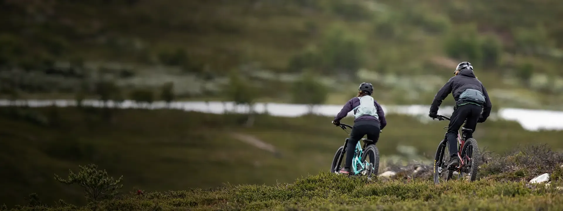 Two mountain bikers riding with compact Thule cycling packs