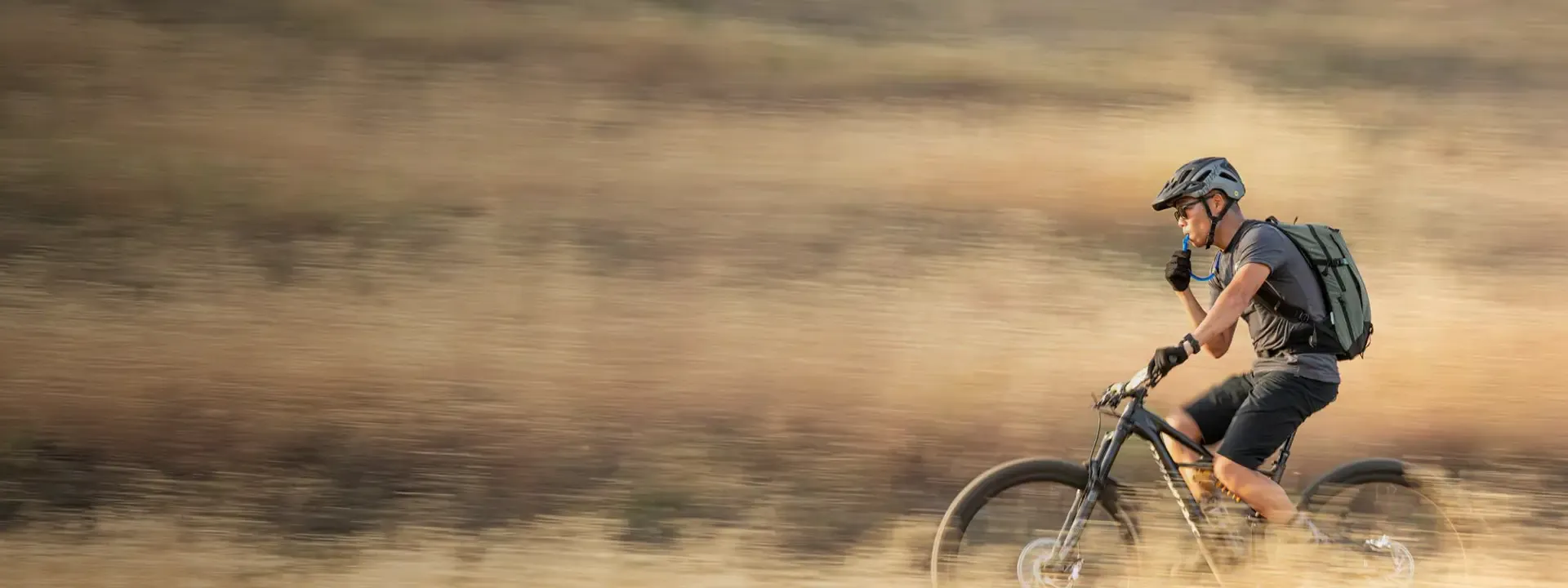 Mountain biker drinking from a hydration pack while riding