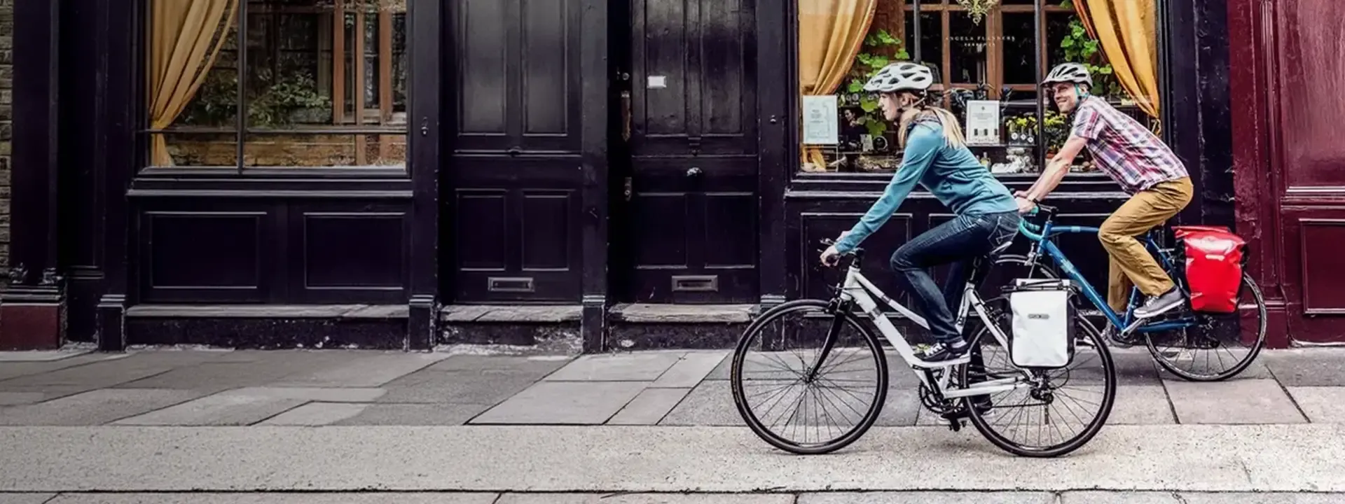 Two urban cyclists riding bikes fitted with rear pannier bags
