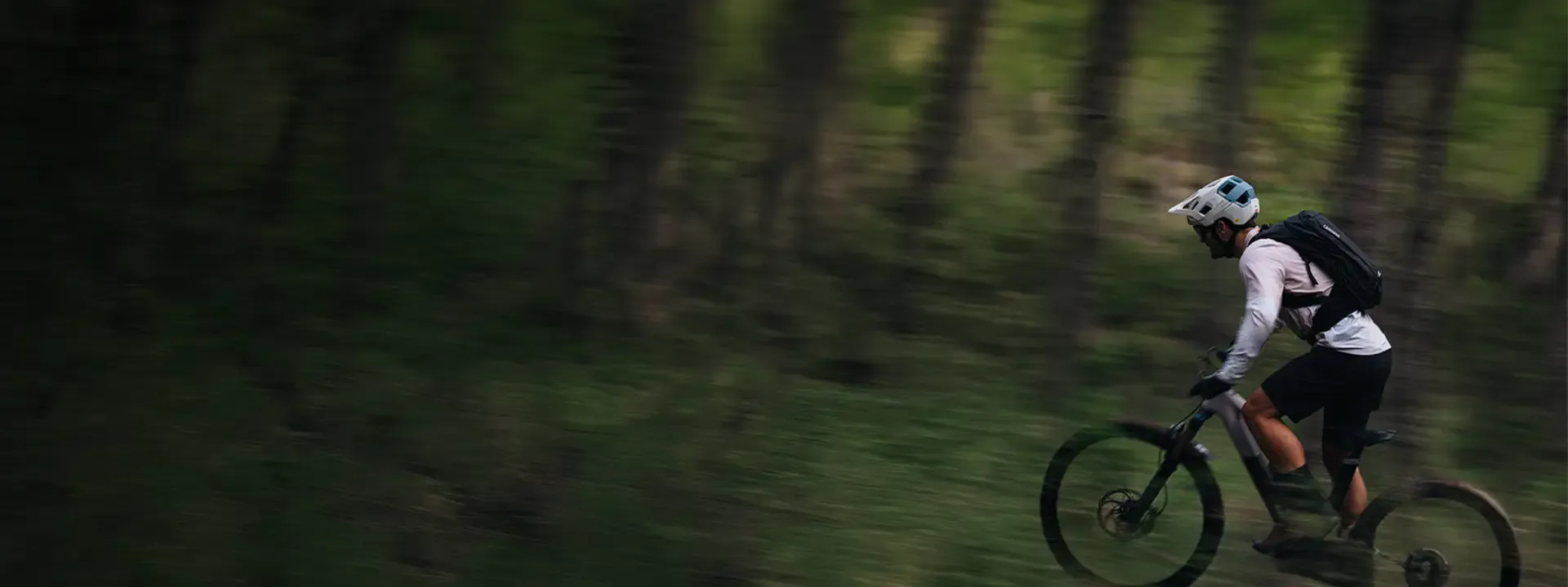 Mountain biker wearing a hydration pack while riding through woodland