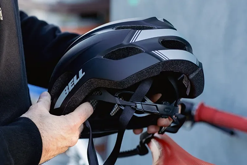 Cyclist adjusting helmet straps and dial-fit system