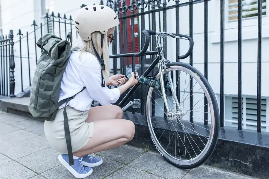 Female cyclist secures her bike to a railing with a portable chain lock