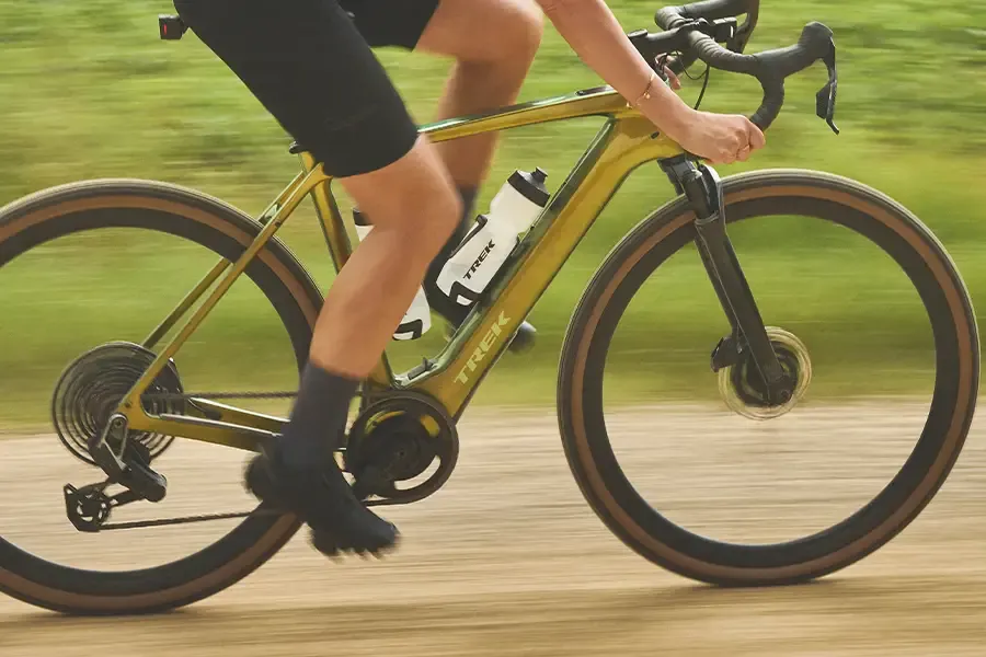 Cyclist riding a gravel bike with a bottle in a frame-mounted cage.