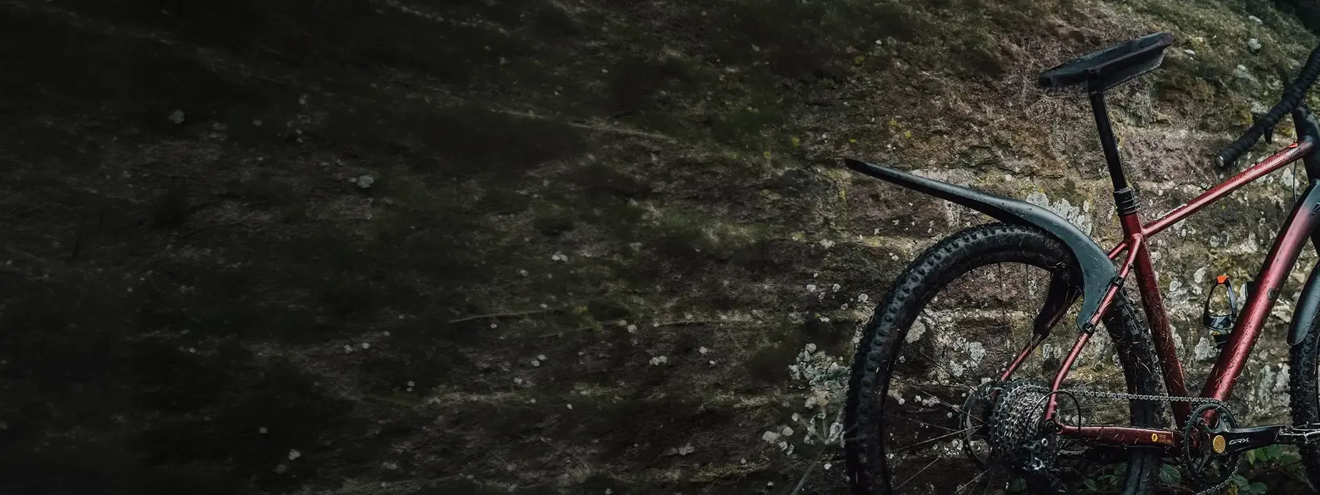 Mountain bike fitted with a Mudhugger rear mudguard beside a wet trail