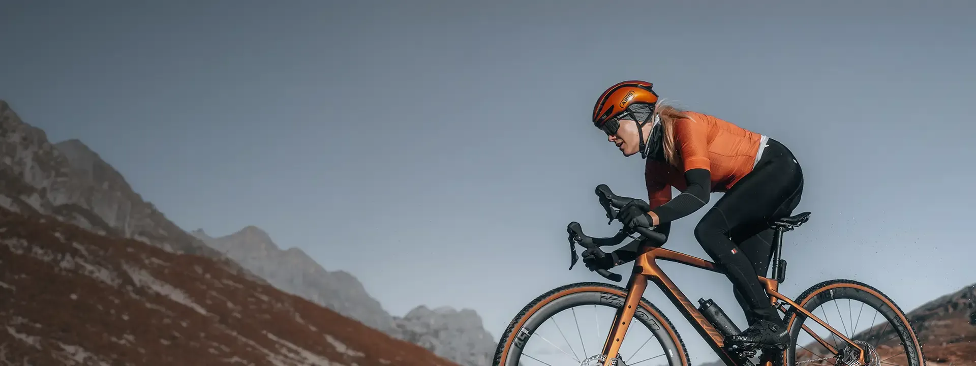 Gravel cyclist climbing mountain roads wearing thermal cycling arm warmers in cool weather conditions