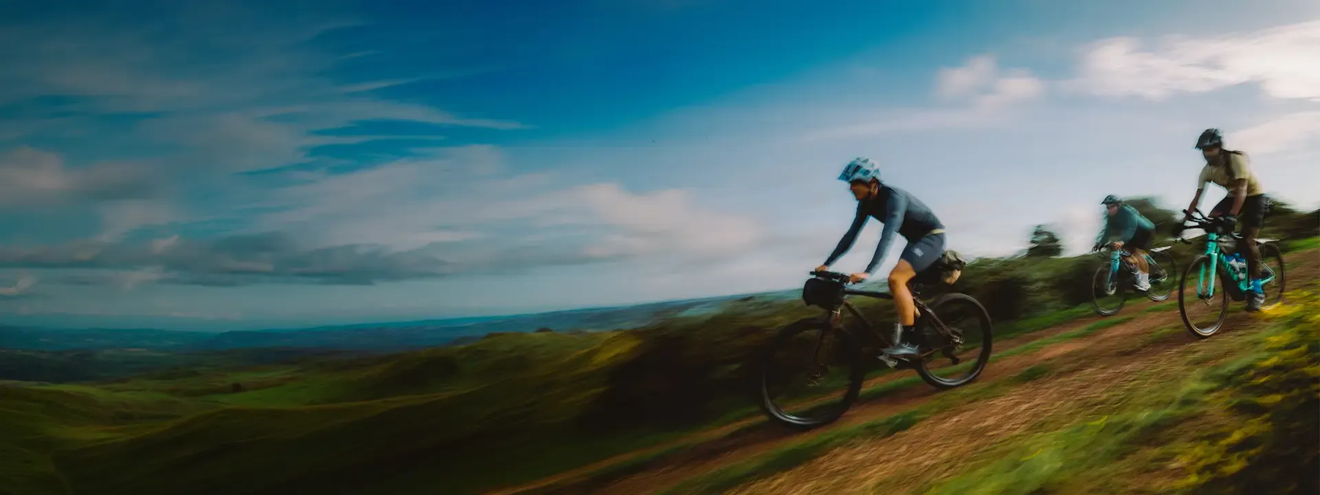 Three mountain bikers descending an exposed hillside trail