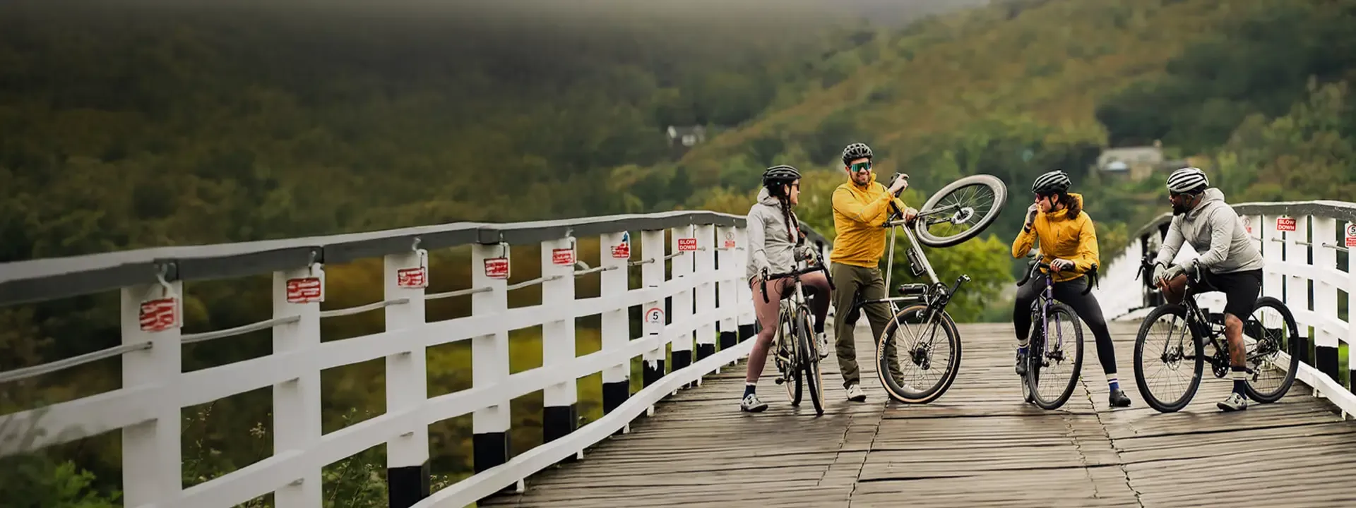 Group of cyclists with mountain bikes gathered on a wooden bridge