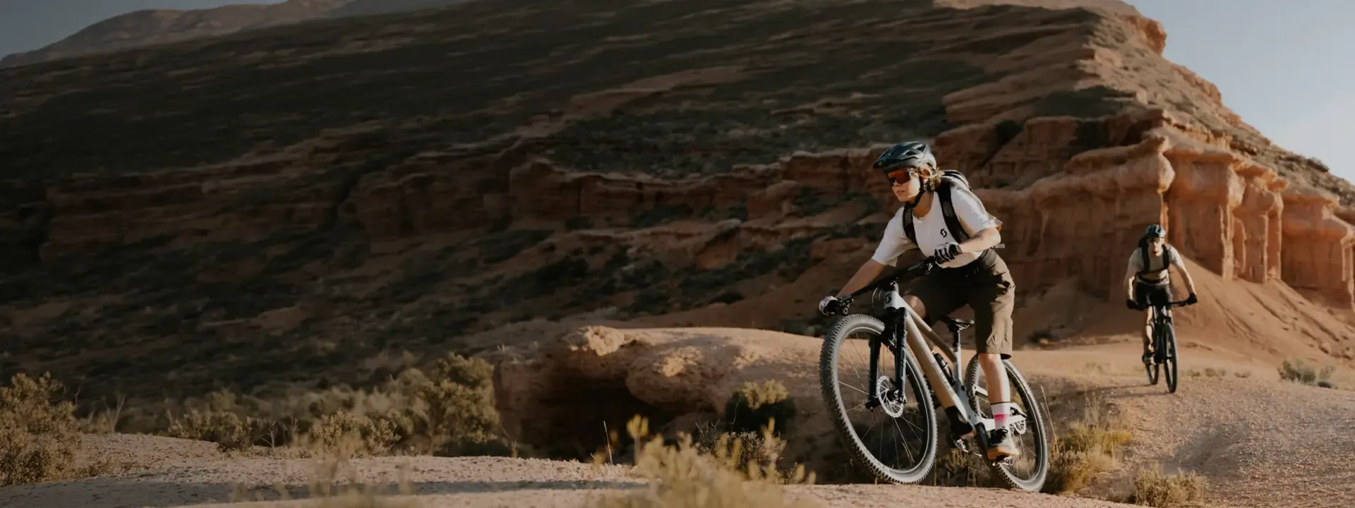 Two mountain bikers riding across rocky desert terrain