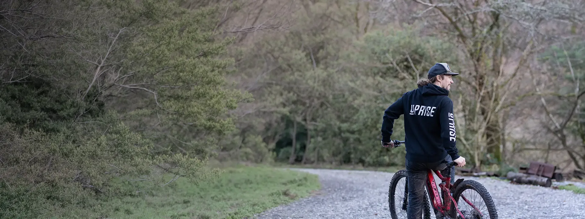 Uprise mountain biker paused with a bike on a quiet woodland track