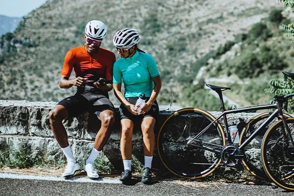 Two cyclists chatting by the side of the road wearing Road cycling clothing