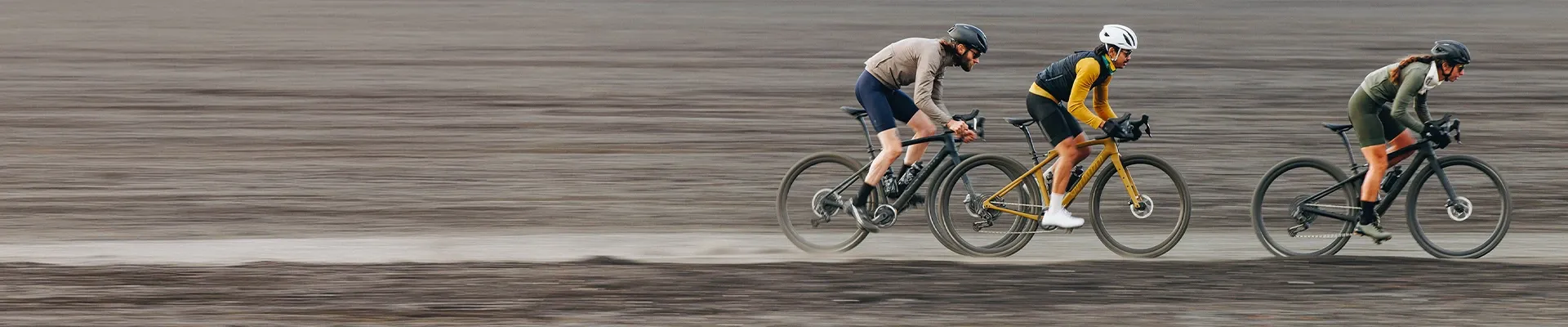 Three gravel road cyclists riding fast in road and off-road clothing