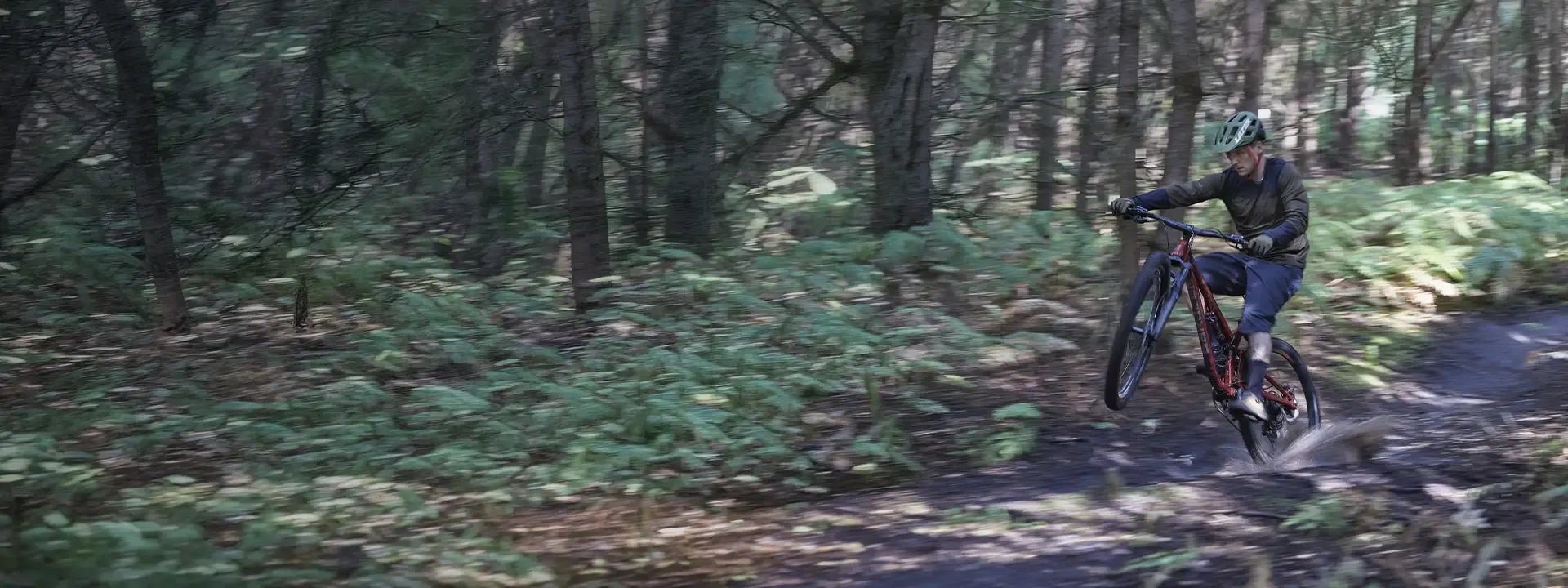 Mountain biker riding wet forest trails wearing waterproof baggy mountain bike shorts