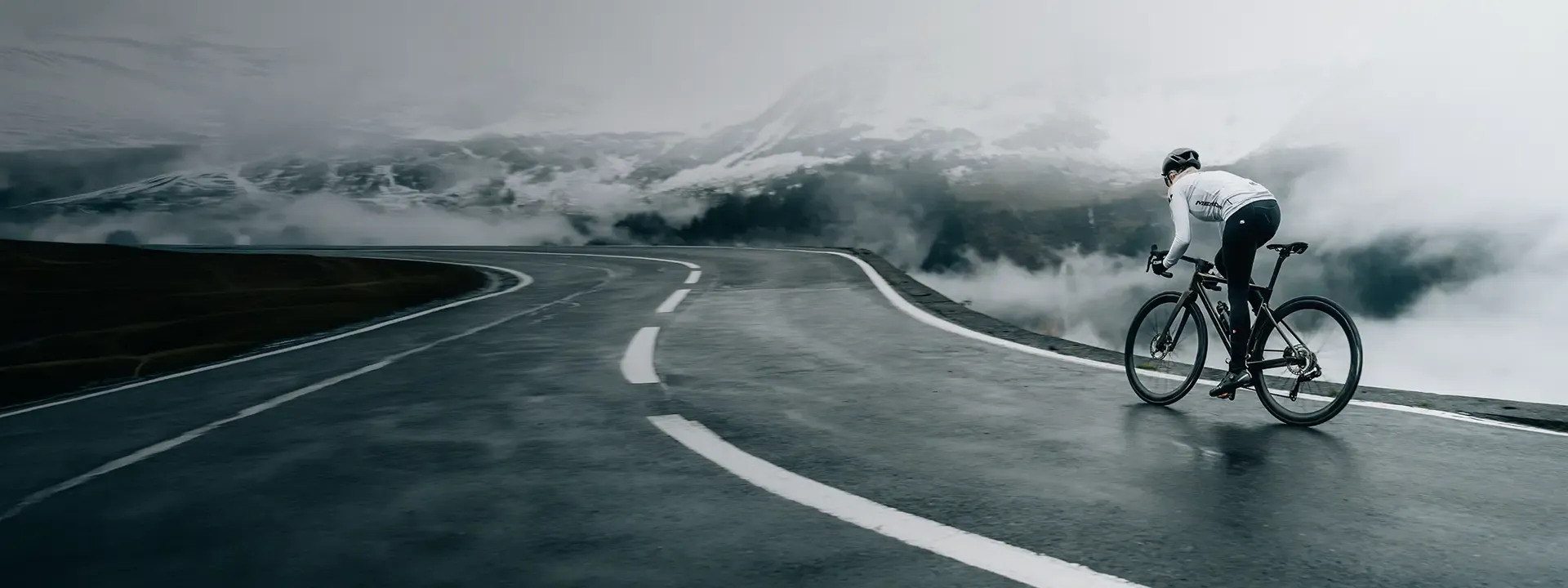 Road cyclist riding through cold windy mountain conditions wearing windproof cycling bib tights