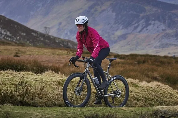 Female cyclist climbing a mountain road waering a waterproof road cycling jacket