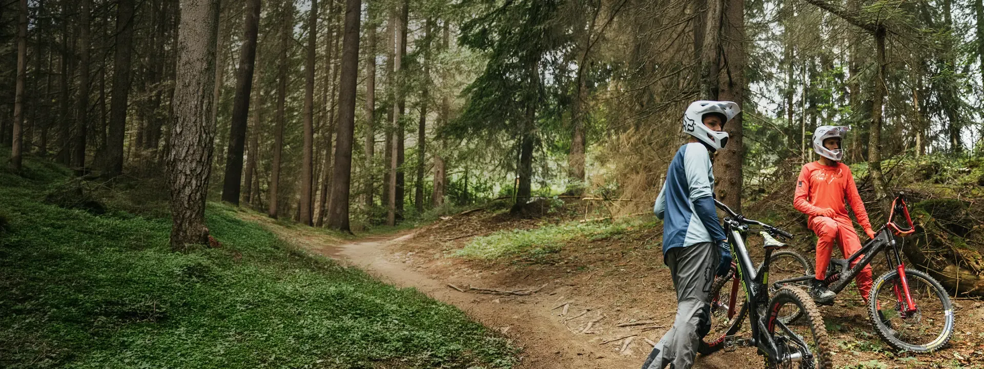 Mountain bikers wearing long sleeve cycling jerseys in woodland trail conditions