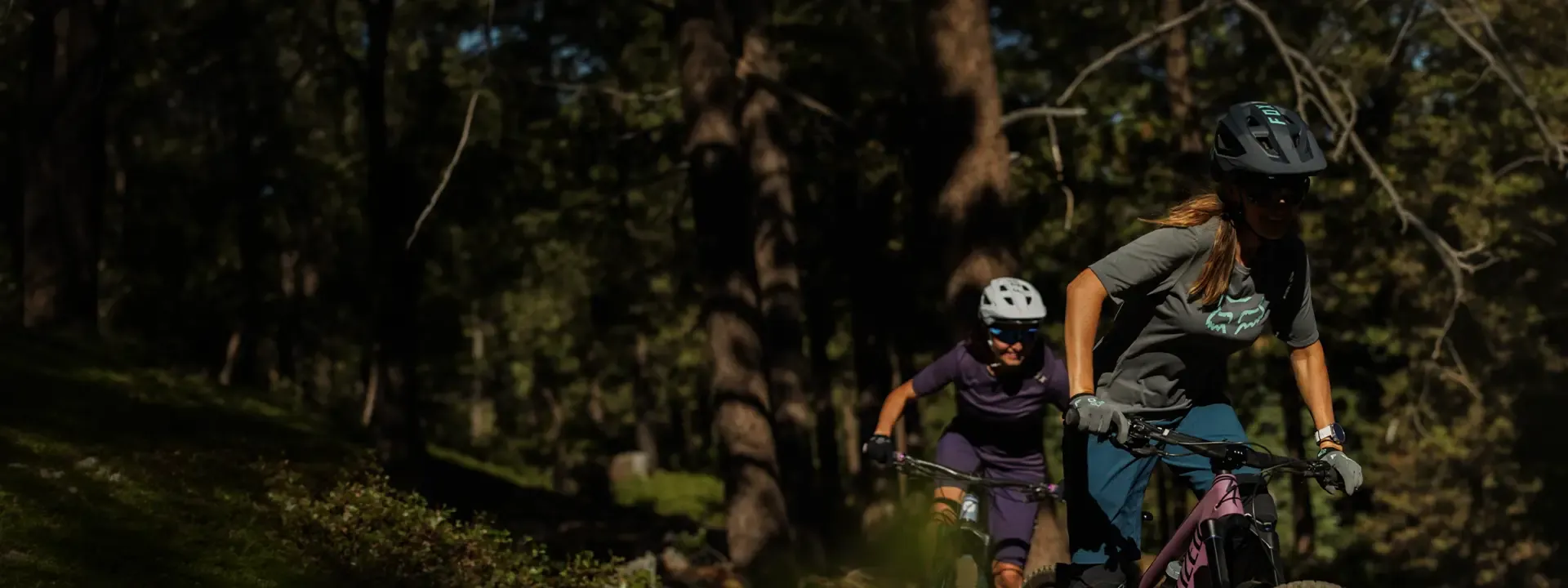 Women mountain bikers riding woodland trails wearing breathable cycling jerseys