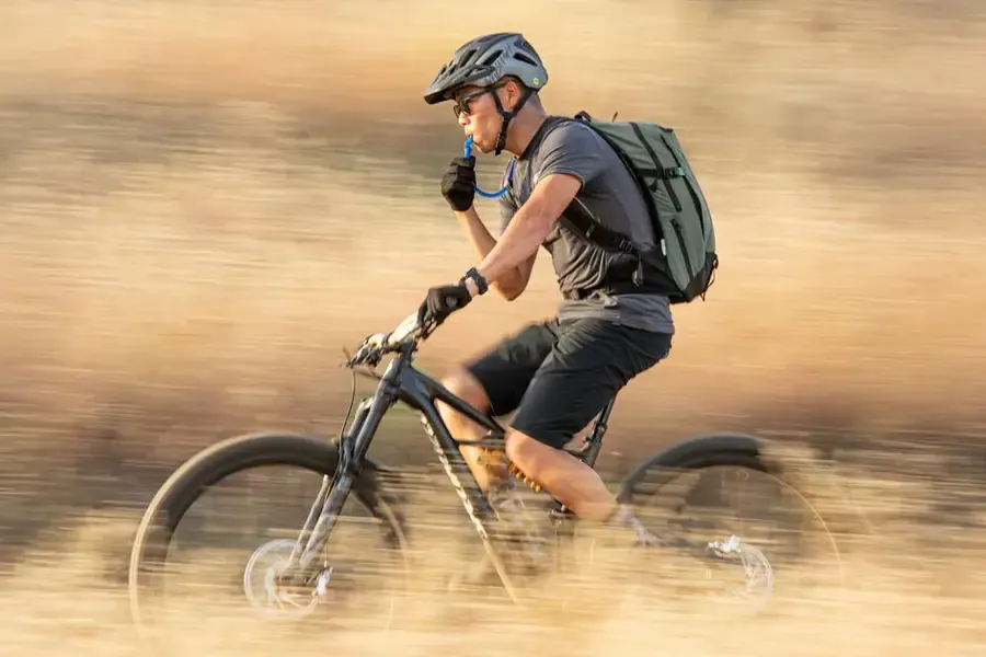MTB rider wearing a cycling hydration pack with drinking hose