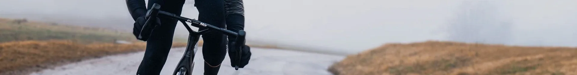 Close-up action shot of gloved hands on road bike handlebars in winter conditions