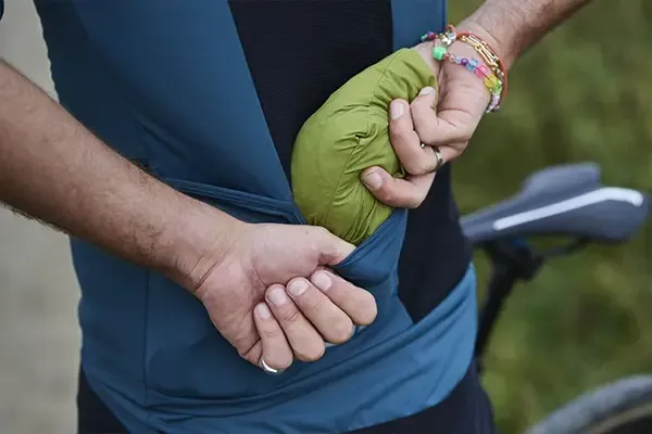 Packable cycling jacket folded into jersey pocket