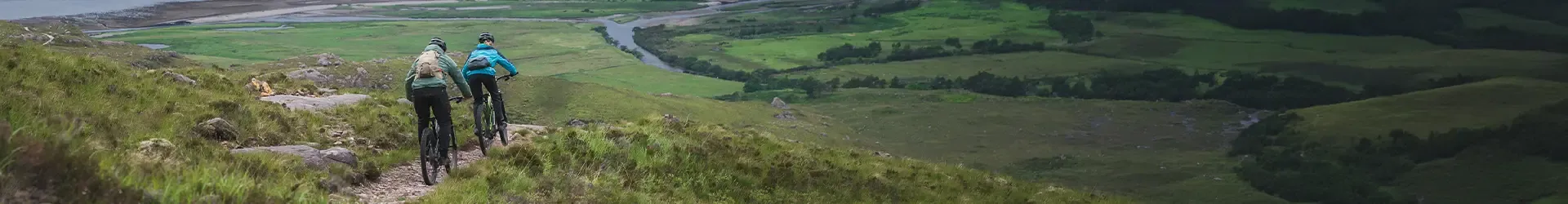 Mountain bikers riding singletrack in wet weather in technical jackets