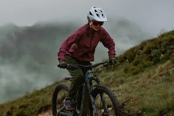 mountain biker wearing a waterproof cycling jacket on a climb in wet conditions