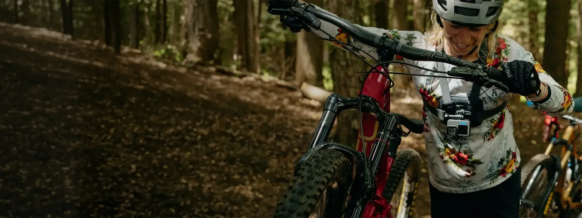 Mountain biker pushing a bike through a woodland trail
