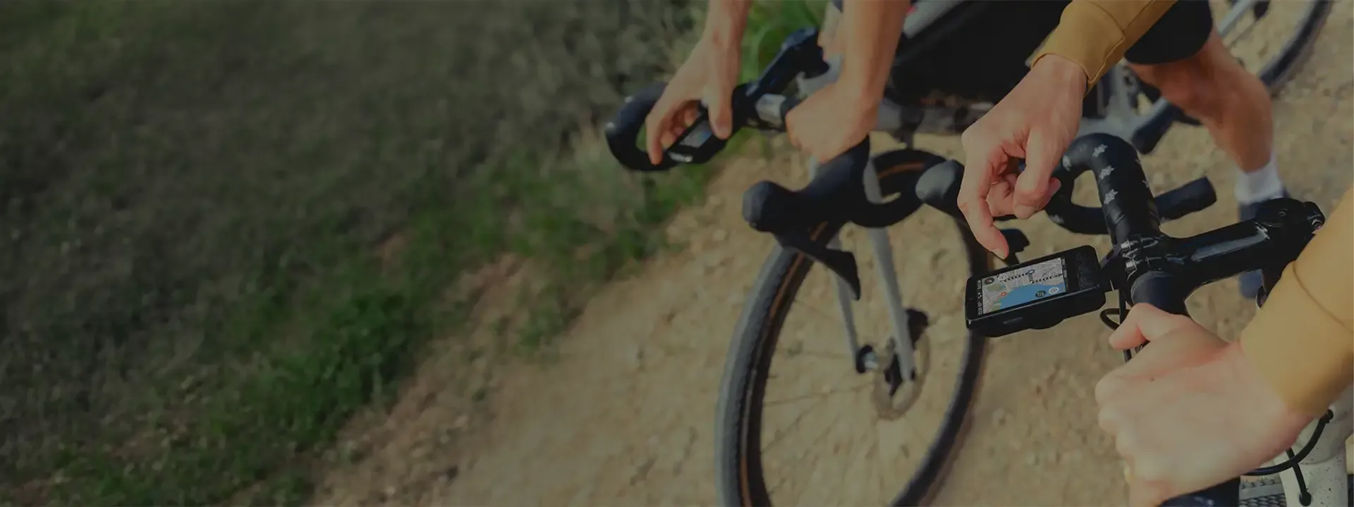 Cyclist checking a GPS bike computer mounted on drop handlebars while riding
