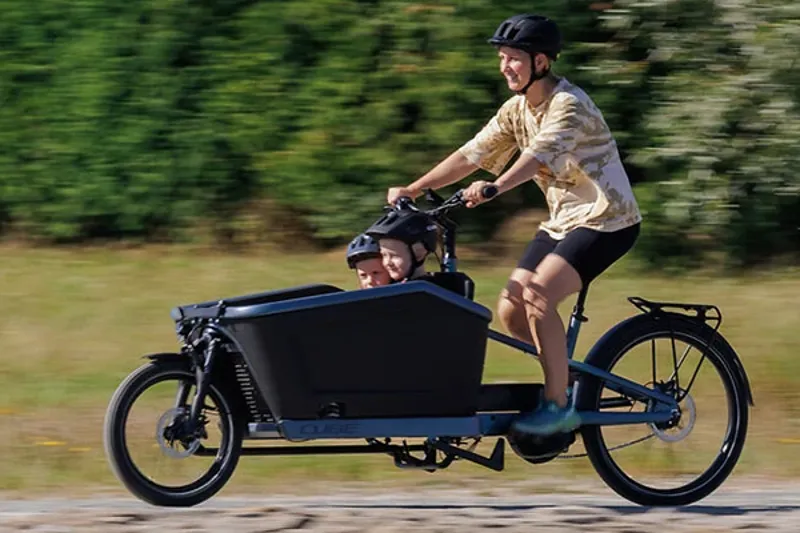 Woman riding an Electric cargo bike carrying two kids