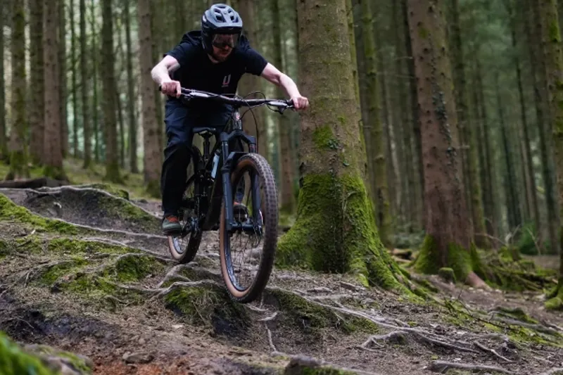 riding an electric mountain bike over rooty terrain closeup