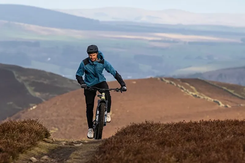 Riding a Marin eMTB up a climb on open moorland