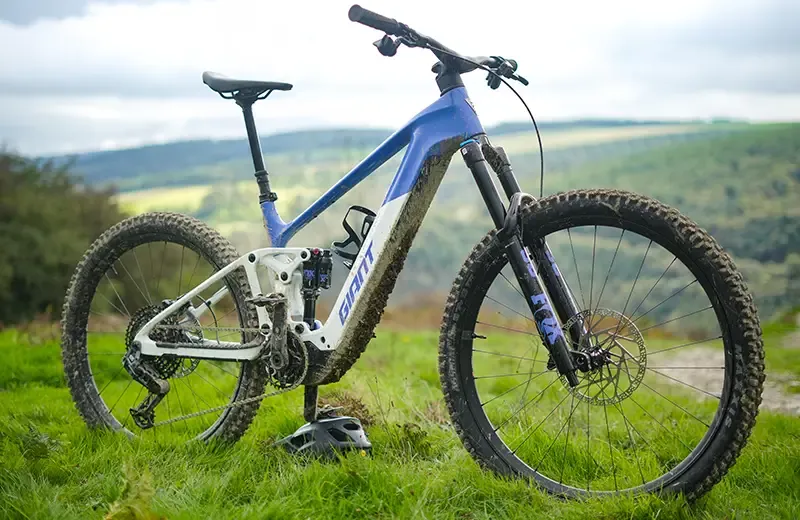 Giant Trance Advanced E+ 1 standing on grass beside the trails