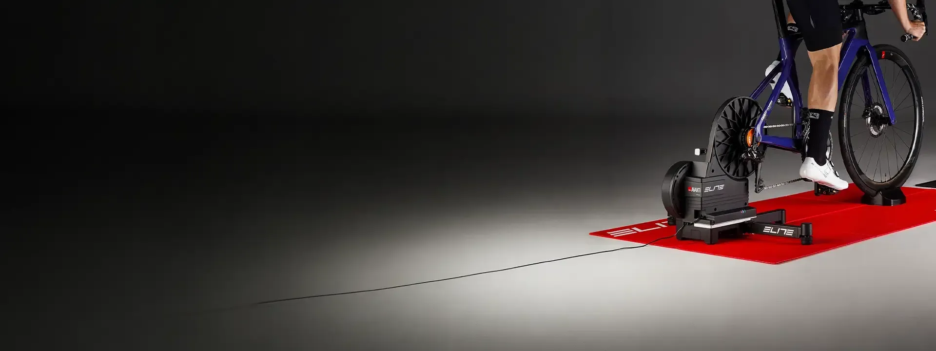 Cyclist riding a bike on an Elite indoor trainer on a red training mat