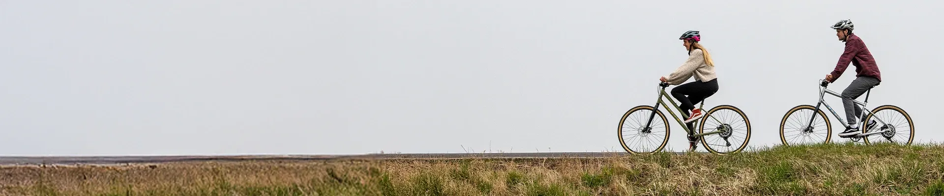 Man and woman riding Marin hybrid bikes along the skyline