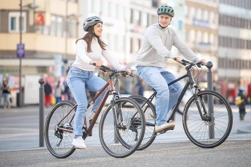 Young couple riding Orbea hybrid bikes in the city