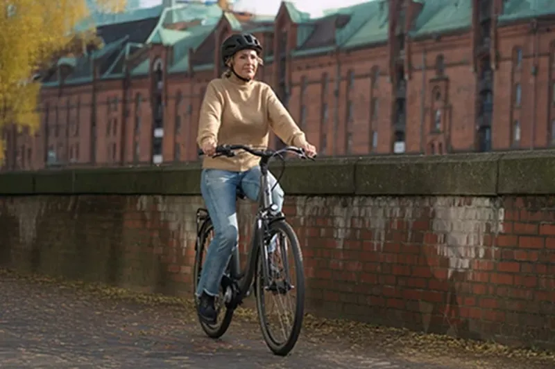 Woman riding a hybrid bike with a suspension fork riding on brick path