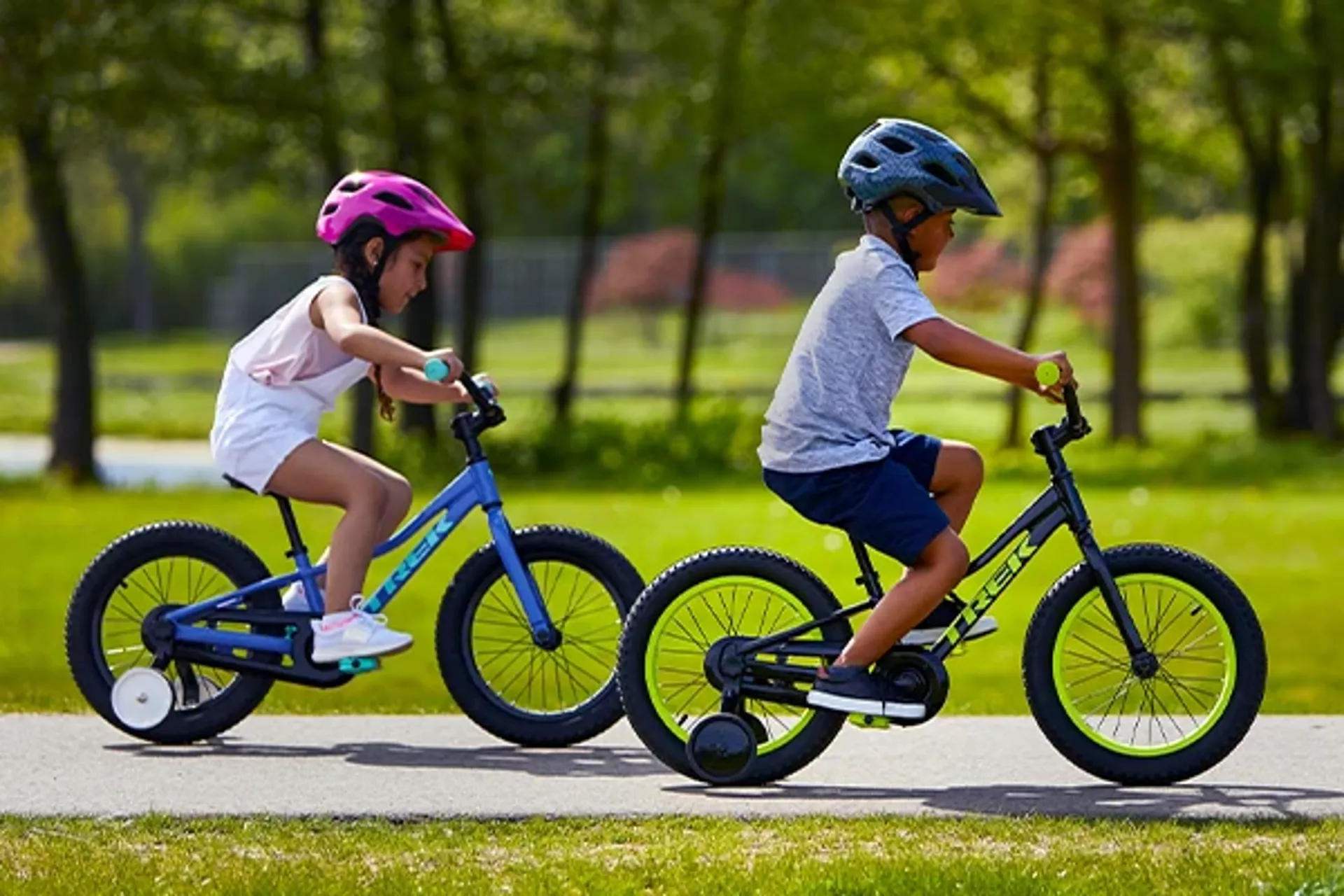 Two young children riding small pedal bikes with stabilisers