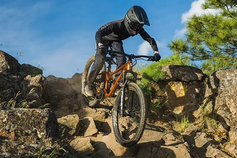 Junior rider on rocky terrain on a modern Giant full-suspension 27.5 inch junior mountain bike