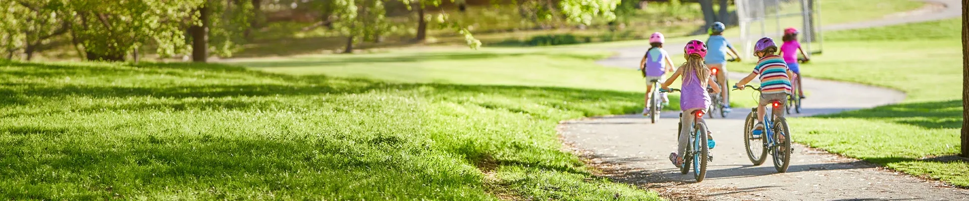 Group of children riding bikes through the park on a sunny day