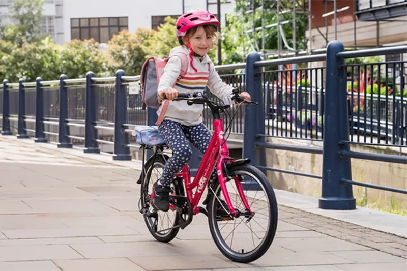 Child riding a Frog City 53 hybrid bike on an urban cycle path