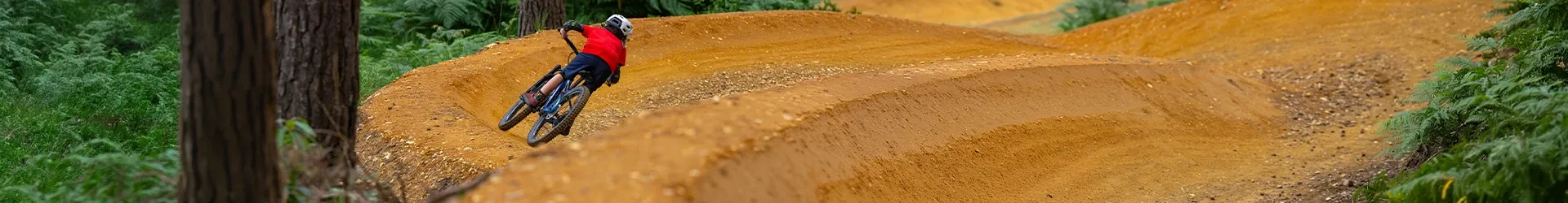 Junior rider railing a berm on flowing trails in the woods