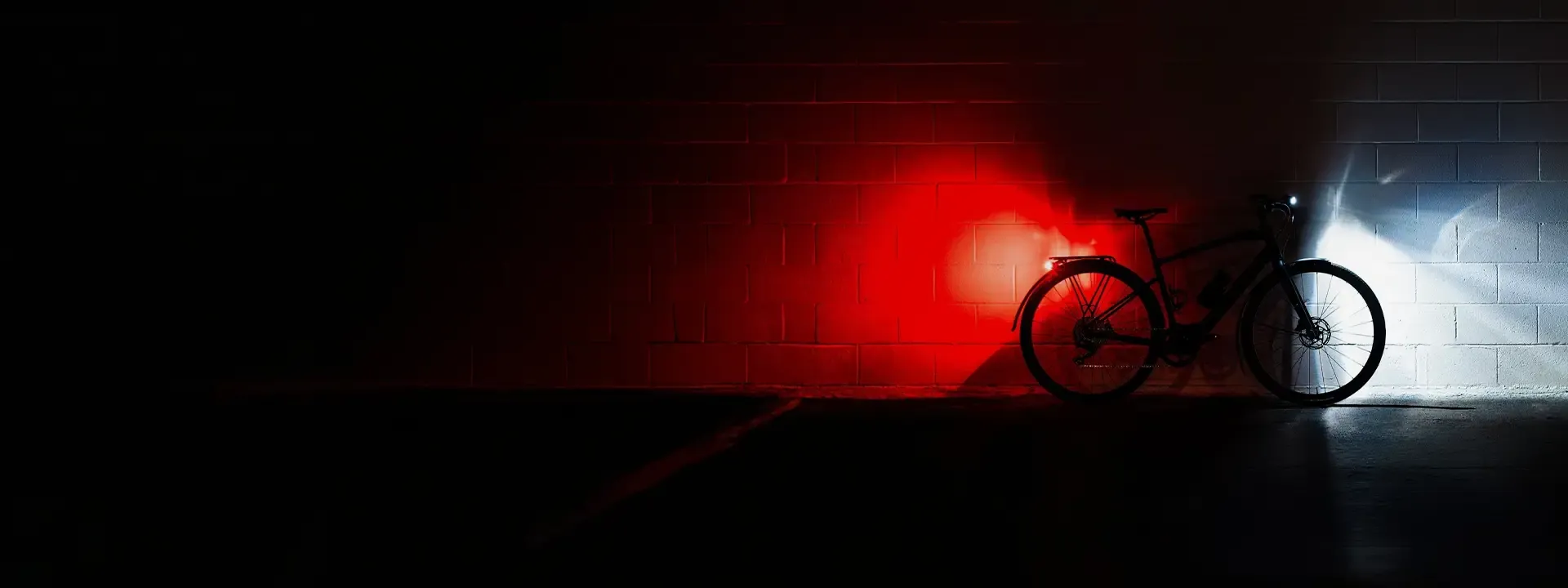 Bicycle silhouetted against red rear and white front light beams in the dark