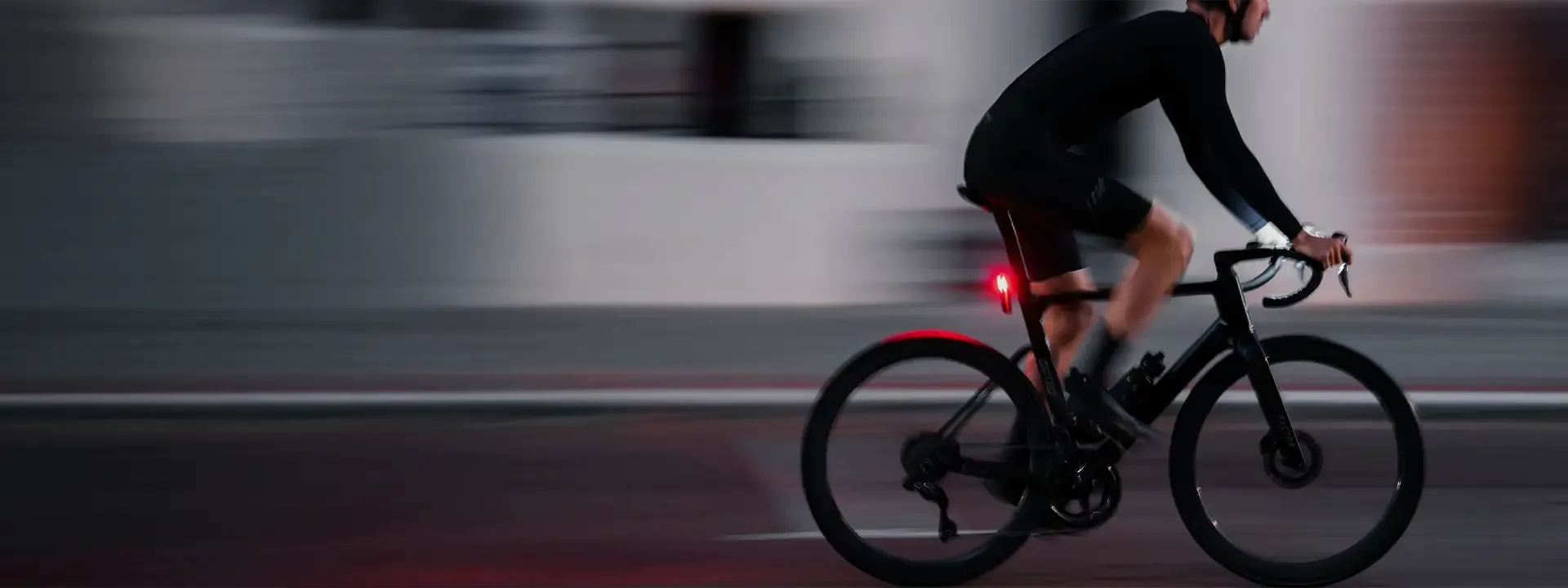 Cyclist riding through town with a red rear bike light illuminated