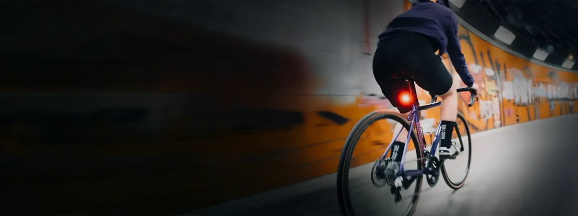 Cyclist riding through a tunnel with a red rear bike light illuminated