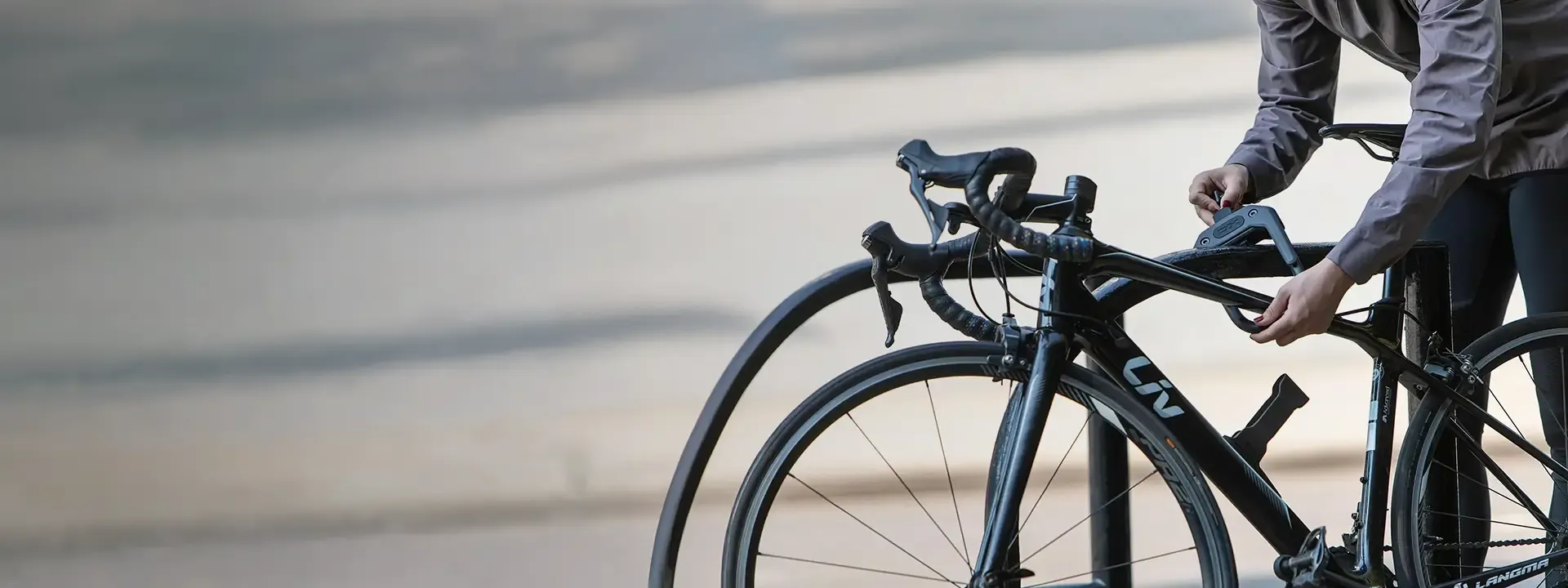 Cyclist preparing to secure a road bike with a D-lock